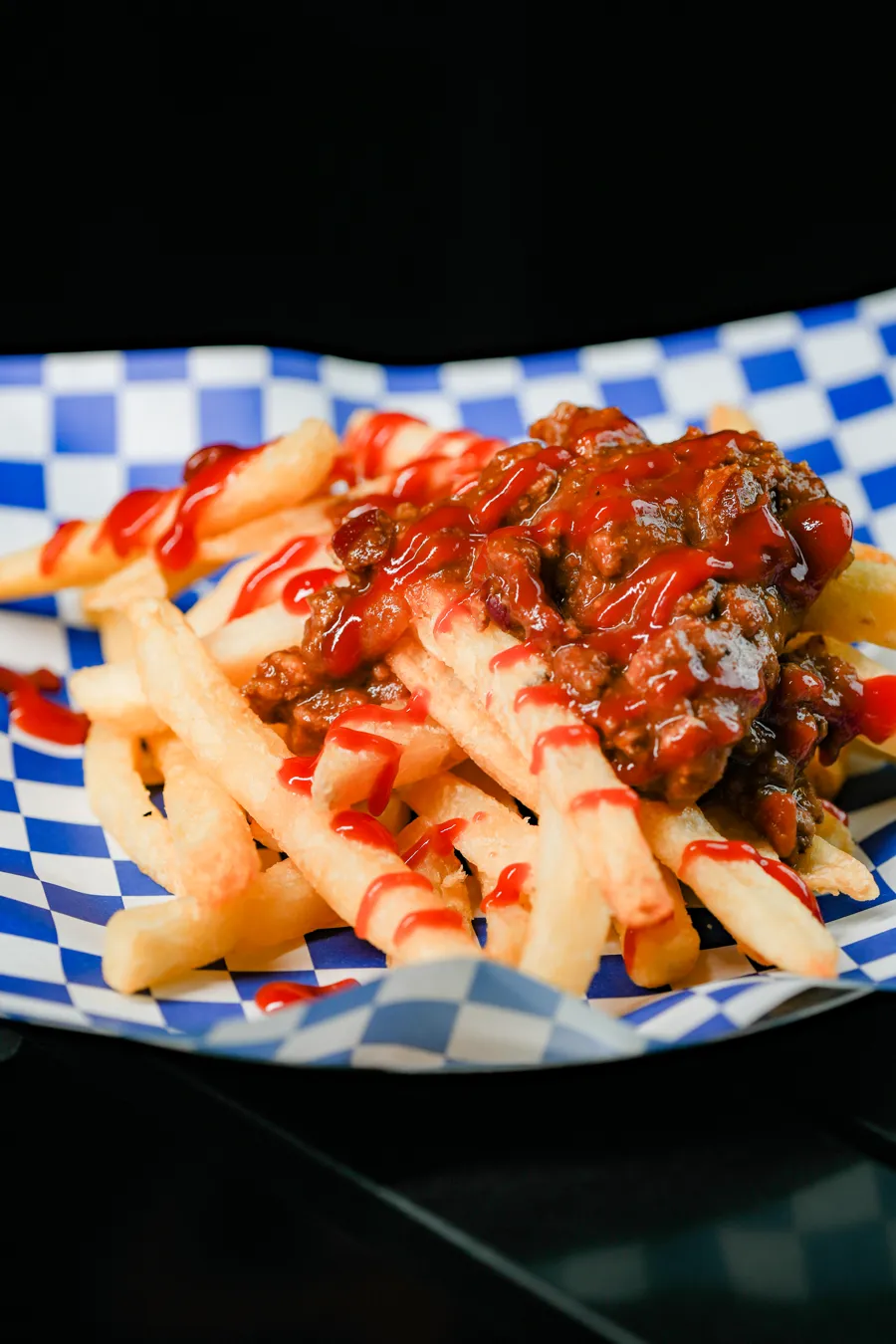 Meat sauce fries from the Hotdogray fried food list: golden fries piled with meat sauce and drizzled with ketchup, on blue checkered paper