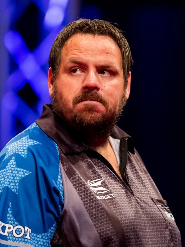 英格蘭飛鏢選手 Adrian Lewis 舞台特寫,留著鬍子、神情專注