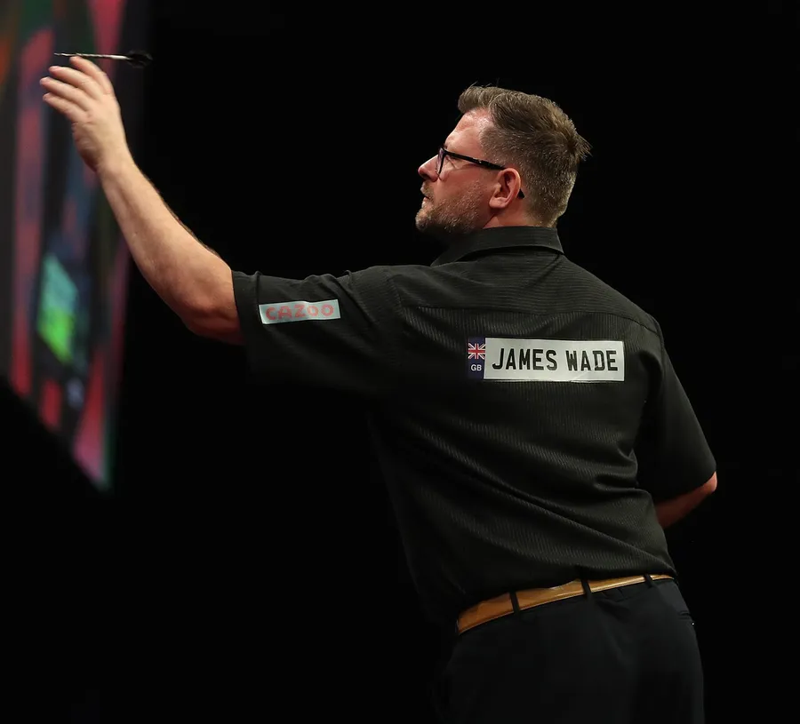 El jugador de dardos zurdo James Wade, de espaldas, levanta el brazo izquierdo para lanzar