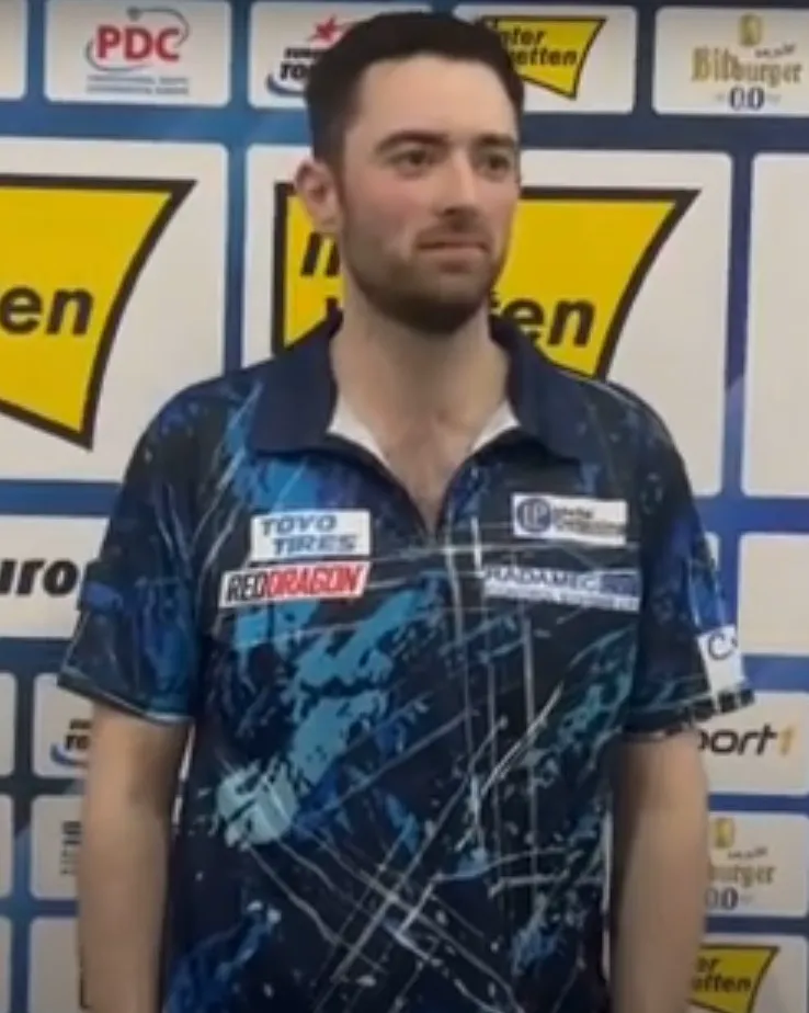 英格蘭飛鏢選手 Luke Humphries 賽事畫面特寫，身穿藍色隊服